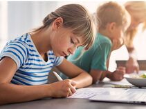 A child smiling while working at a classroom table