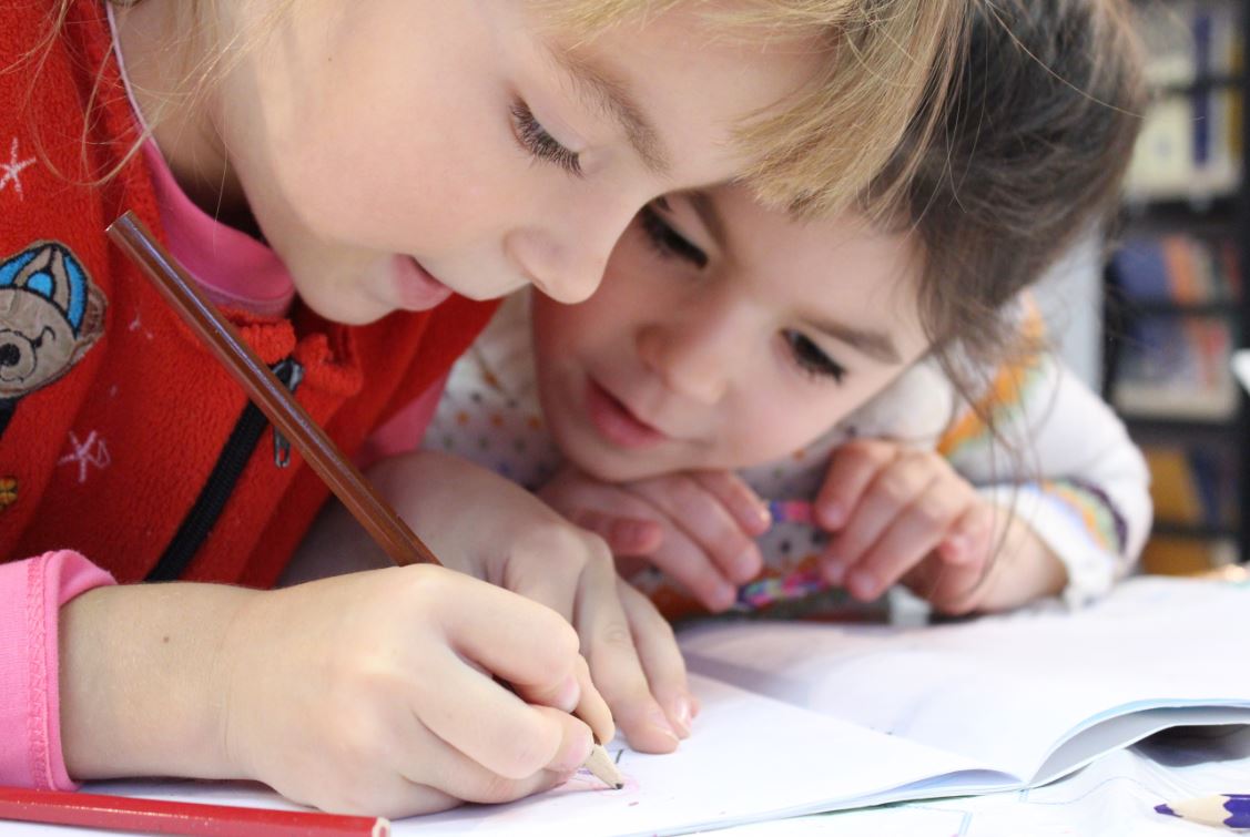 Two children collaborating closely over their work